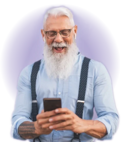 White haired, long bearded guy wearing a button down shirt with rolled sleeves showing his tatoos, smiling and looking at his cellphone 